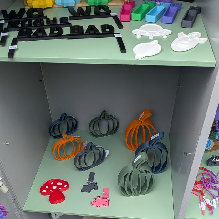 Kleine 3D-gedruckte Kürbisse und Pilze auf einem Regalbrett der Box